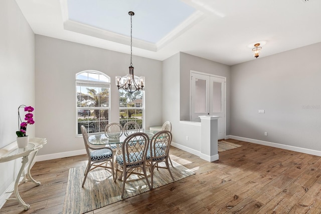 dining area with a chandelier, light hardwood / wood-style floors, and a tray ceiling