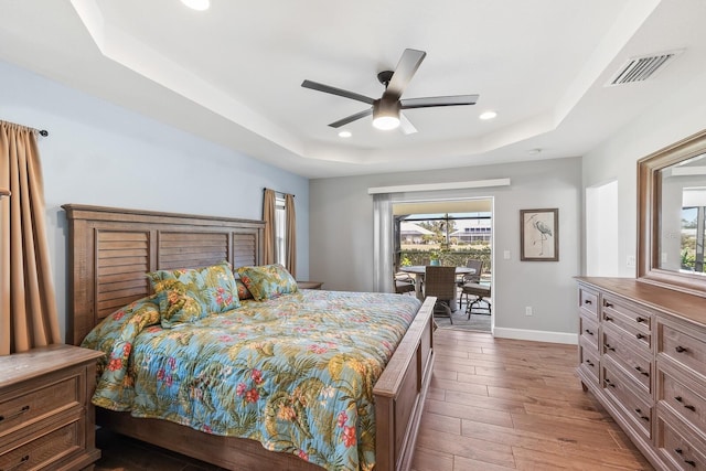 bedroom featuring access to outside, a raised ceiling, and ceiling fan