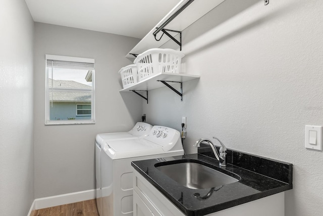 clothes washing area with hardwood / wood-style flooring, separate washer and dryer, and sink