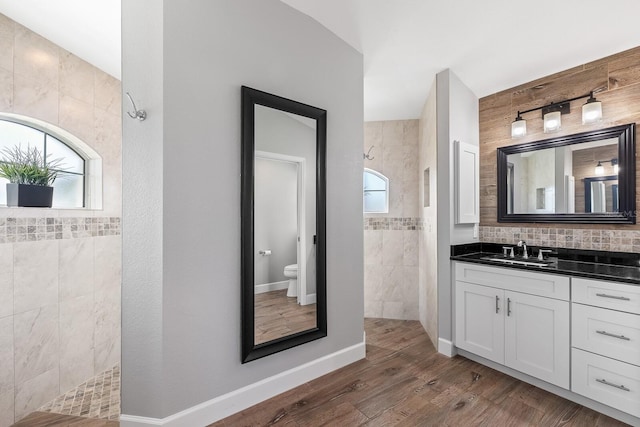 bathroom featuring vanity, hardwood / wood-style floors, a wealth of natural light, and tiled shower