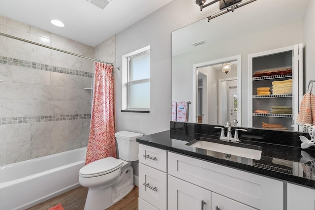 full bathroom with hardwood / wood-style flooring, vanity, shower / bath combination with curtain, and toilet