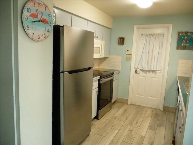 kitchen featuring stainless steel appliances, white cabinetry, light wood-type flooring, and decorative backsplash