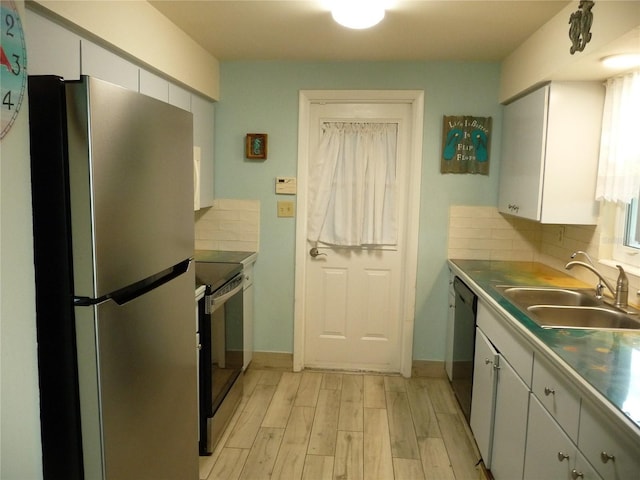 kitchen featuring sink, appliances with stainless steel finishes, white cabinets, decorative backsplash, and light wood-type flooring