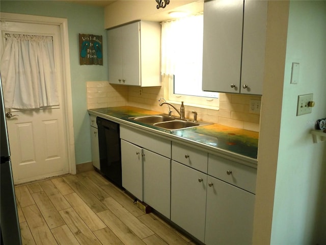 kitchen featuring white cabinetry, black dishwasher, sink, and backsplash