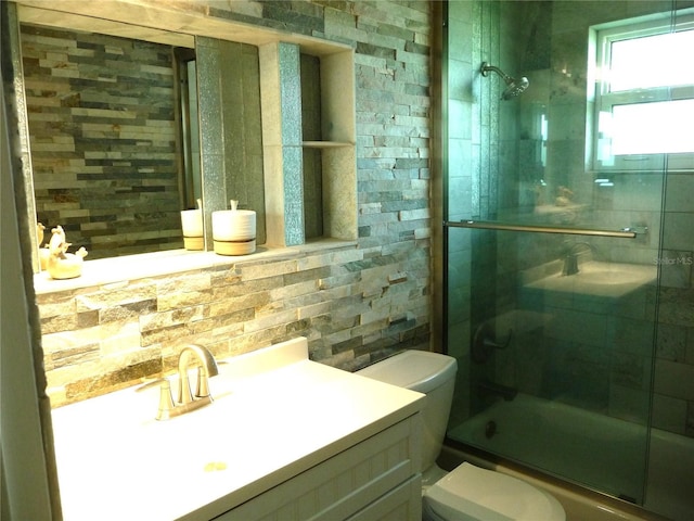 full bathroom featuring tasteful backsplash, vanity, toilet, and combined bath / shower with glass door