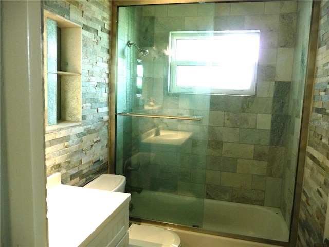 full bathroom featuring vanity, bath / shower combo with glass door, and toilet