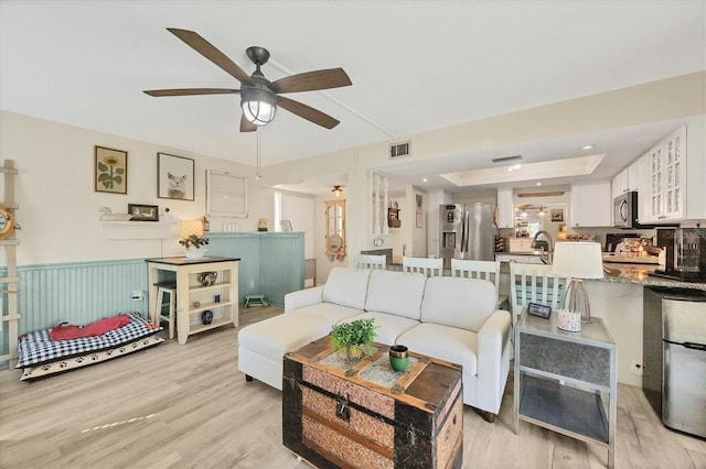 living room with ceiling fan, sink, and light hardwood / wood-style flooring