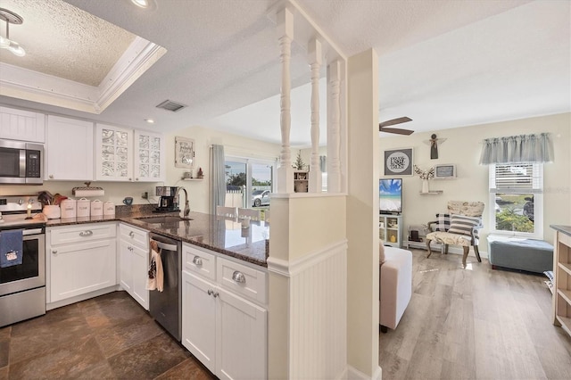 kitchen with sink, appliances with stainless steel finishes, dark stone countertops, a textured ceiling, and white cabinets