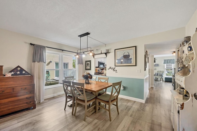 dining space with a textured ceiling and light wood-type flooring