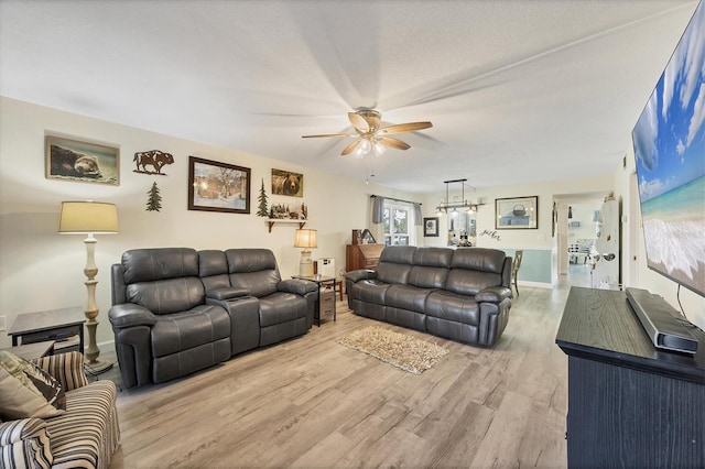 living room with ceiling fan, a textured ceiling, and light wood-type flooring