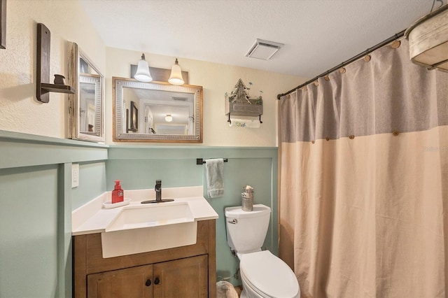 bathroom featuring a shower with curtain, vanity, toilet, and a textured ceiling