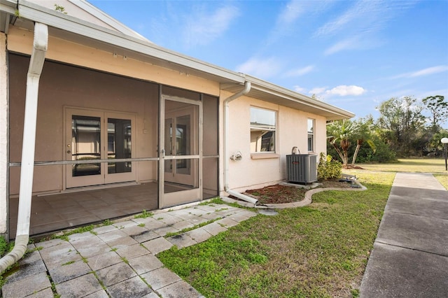 view of side of home featuring a yard, a patio area, a sunroom, and central air condition unit