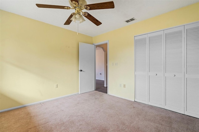 unfurnished bedroom with light colored carpet, ceiling fan, and a closet