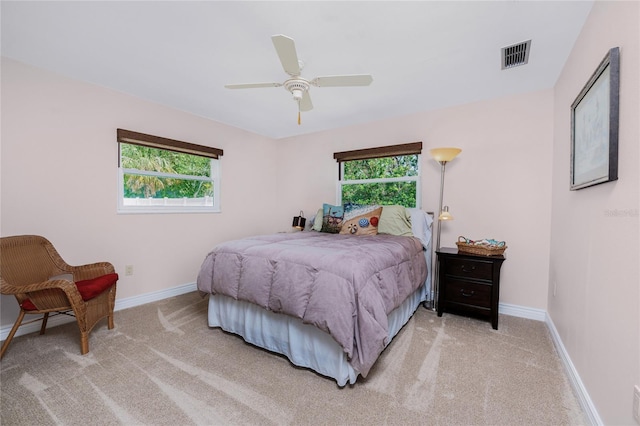 carpeted bedroom with multiple windows and ceiling fan