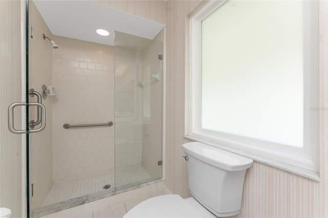 bathroom with a shower with shower door and toilet