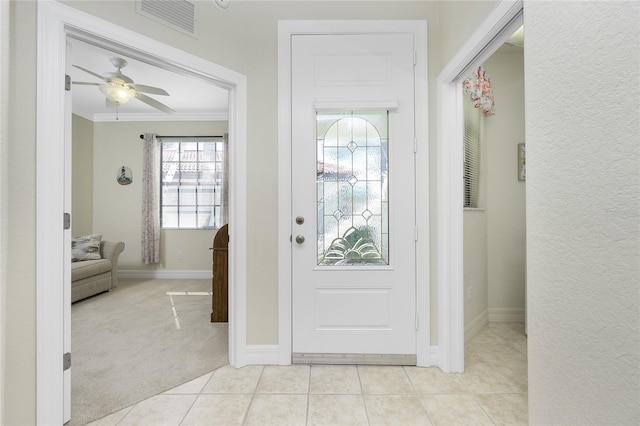 carpeted foyer featuring ornamental molding and ceiling fan