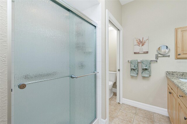 bathroom featuring vanity, toilet, a shower with shower door, and tile patterned flooring