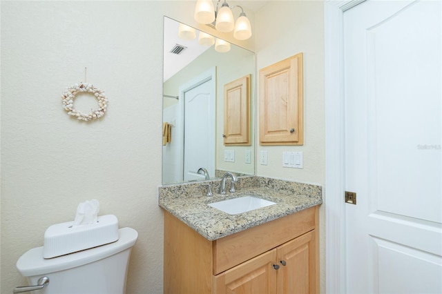 bathroom with an inviting chandelier, vanity, and toilet