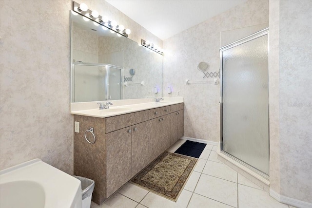 bathroom featuring tile patterned floors, a stall shower, double vanity, and a sink