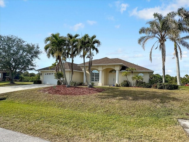 mediterranean / spanish home featuring stucco siding, a front lawn, an attached garage, and driveway