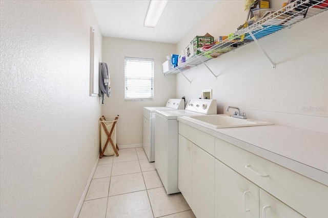 laundry room featuring light tile patterned floors, baseboards, cabinet space, a sink, and washing machine and dryer