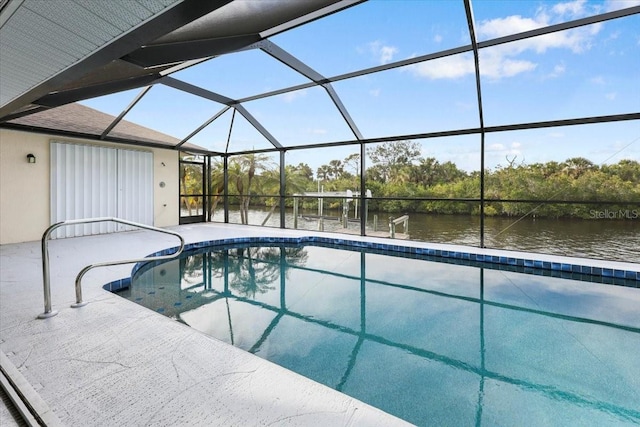 pool with glass enclosure, a patio, and a water view