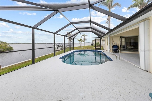 pool with a patio area, glass enclosure, and a water view