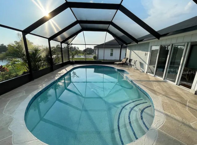 view of swimming pool featuring glass enclosure and a patio area