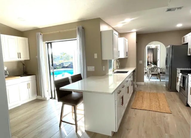 kitchen featuring white cabinetry, a breakfast bar, light hardwood / wood-style floors, and sink