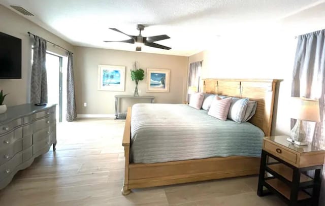 bedroom with a textured ceiling, light hardwood / wood-style flooring, and ceiling fan