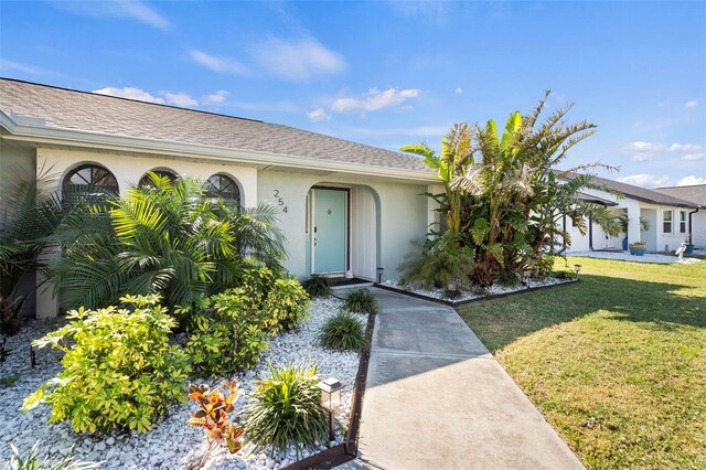 254 Mark Twain Ln, Rotonda West, FL 33947 - property entrance featuring a yard, stucco siding, and roof with shingles