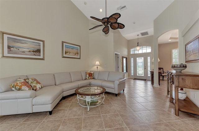 tiled living room with ceiling fan and a high ceiling