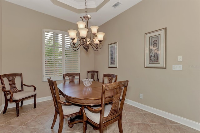 tiled dining area with a raised ceiling, ornamental molding, and a notable chandelier