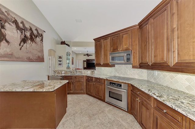 kitchen featuring lofted ceiling, decorative backsplash, light stone countertops, and appliances with stainless steel finishes