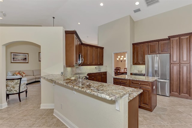 kitchen featuring a kitchen bar, decorative backsplash, kitchen peninsula, stainless steel appliances, and light stone countertops