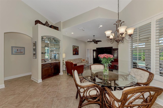 dining space with ceiling fan with notable chandelier, vaulted ceiling, and light tile patterned floors