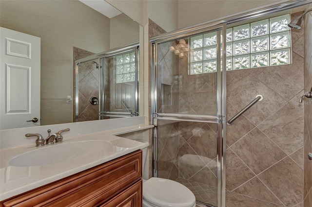 bathroom featuring vanity, toilet, and a shower with door