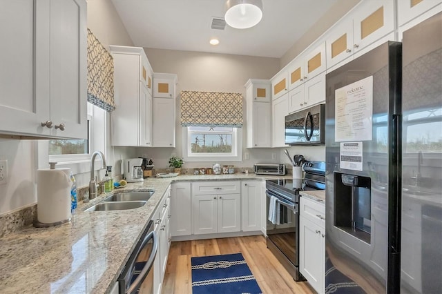 kitchen with white cabinetry, appliances with stainless steel finishes, sink, and light stone counters