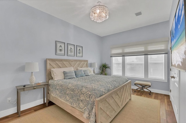 bedroom with light hardwood / wood-style flooring and a chandelier