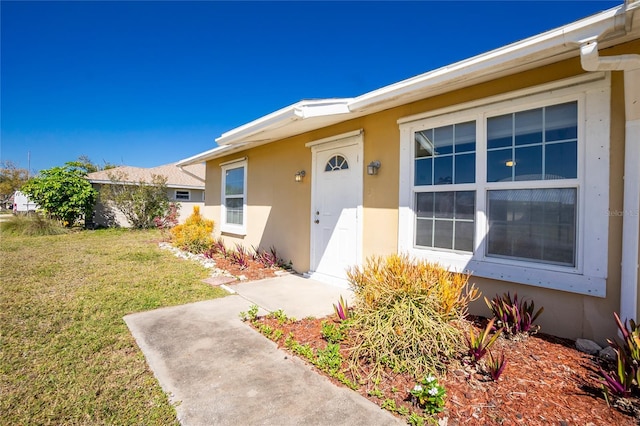 property entrance with a lawn and stucco siding