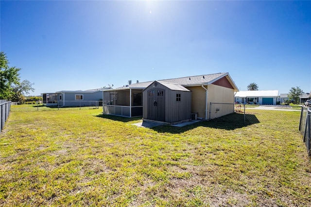 back of property featuring a lawn, a sunroom, a shed, a fenced backyard, and an outdoor structure