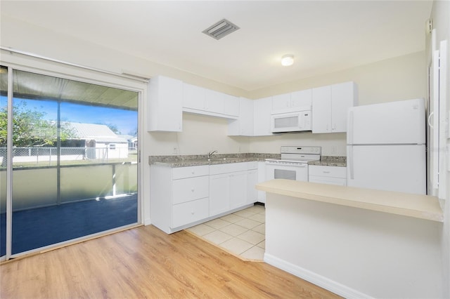 kitchen with white appliances, a sink, visible vents, white cabinetry, and light wood-type flooring