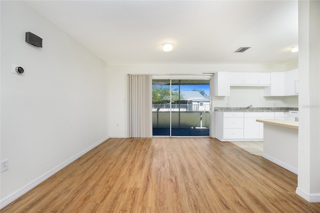 unfurnished living room with visible vents, light wood-style flooring, and baseboards