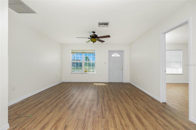 interior space with a ceiling fan, baseboards, visible vents, and wood finished floors