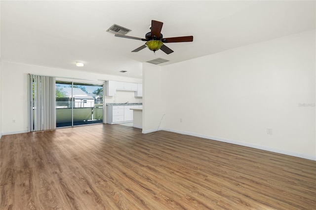 unfurnished living room featuring light wood finished floors, baseboards, visible vents, and a ceiling fan