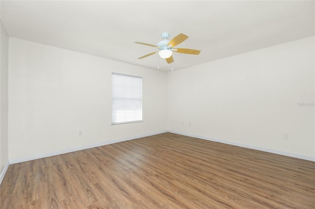 unfurnished room featuring ceiling fan, baseboards, and wood finished floors