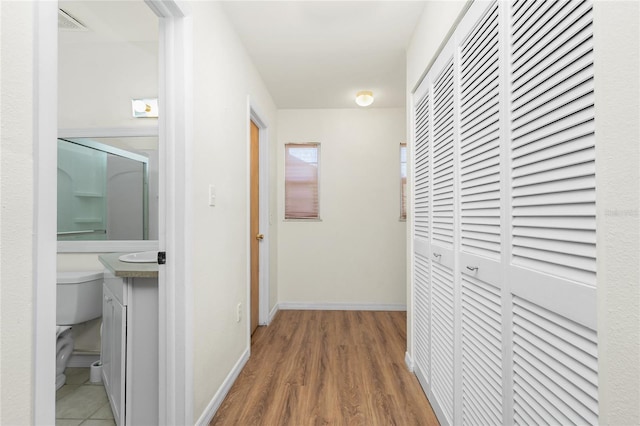 corridor with wood finished floors, visible vents, and baseboards