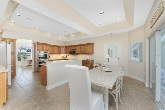 tiled dining room with a raised ceiling and sink