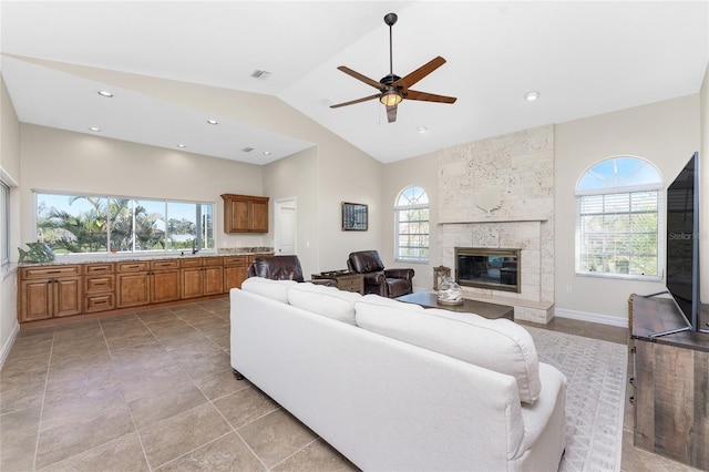 living room featuring ceiling fan, a fireplace, high vaulted ceiling, and a wealth of natural light