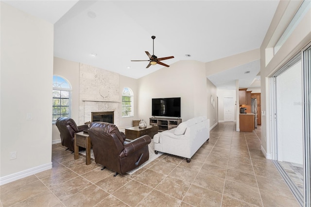 living room featuring a tiled fireplace, high vaulted ceiling, and ceiling fan